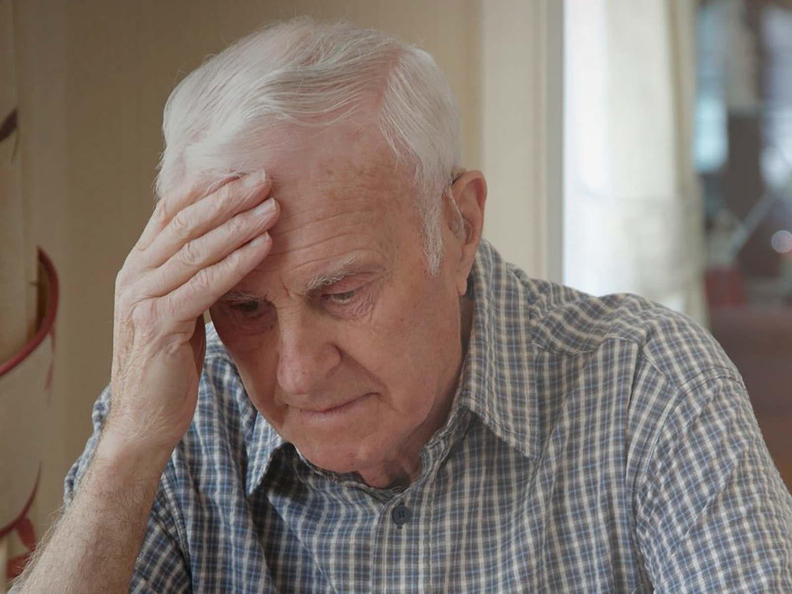 Elderly man sat at table worrying over bills