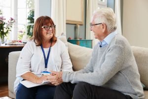 carer chatting with elderly man on sofa