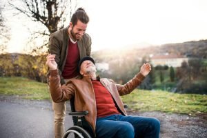 carer pushing happy man in a wheelchair