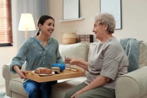 carer serving elderly lady her lunch on a tray-Copy