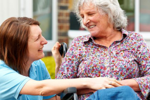 carer chatting with seated elderly lady